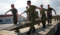 Japan Ground Self-Defense Force 2nd Lt. Akihiro Oyabu, center, helps carry a ramp to the end of a medium-girder bridge Marines and JGSDF members constructed Feb. 1 at Camp Hansen. JGSDF officers spent time with 9th Engineer Support Battalion over a five-week period, learning the different aspects and functions of 9th ESB. Oyabu is an infantryman with 12th Infantry Regiment, 8th Division, Western Army, JGSDF. The Marines are with 9th ESB, 3rd Marine Logistics Group, III Marine Expeditionary Force. 
