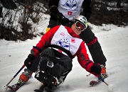 A man skiing on a seated sled on the snow