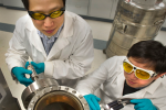 Brookhaven physicists Weidong Si (left) and Qiang Li look into the vacuum chamber where the new high-field iron-based superconductors are made through a process called pulsed-laser deposition.