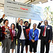 A group of people hold a large check over their heads, which reads Haiti Mobile Money Initiative first to market award