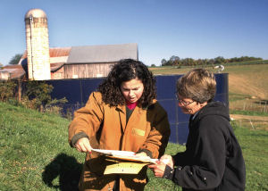 Landowner and NRCS conservationist looking at soil survey report in front of barn.