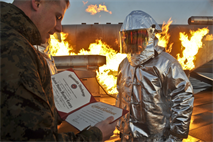 The 16-year veteran Staff Sgt. James Langille, section leader, Aircraft Rescue Firefighter, wears a proximity suit a few yards from an aircraft simulator engulfed in flames during his reenlistment ceremony at the Marine Corps Air Facility on Tuesday. Langille has orders to Marine Corps Air Station New River and will be checking out in March.