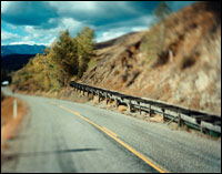 Photo of a winding road with clouds in the background.