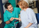 Male nurse assisting wheelchair patient in hospital