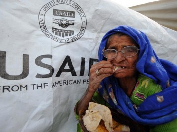 Woman eating piece of bread in front of USAID flag