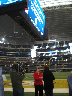 Secretary Napolitano (center) addresses press to discuss DHS role in Super Bowl XLV security with 'If You See Something, Say Something™' on the 'jumbotron' overhead. Photo courtesy of: DHS