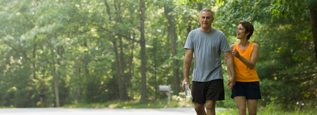 A man and woman hold hands as they take a brisk walk through their neighborhood