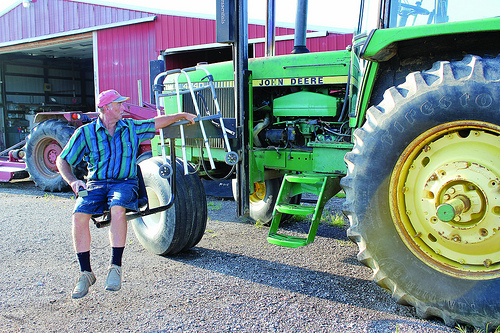 Mark Hosier, paralyzed from the waist down, uses a mechanical lift to board his tractor. Hosier works with the NIFA-funded AgrAbility Program to overcome disabilities and continue working as an agricultural producer.  Photo courtesy of National Swine Registry/Seedstock EDGE.