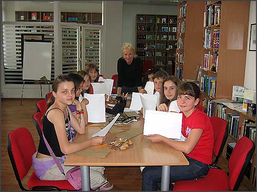 A woman with a group of students in a library setting