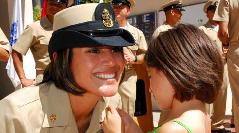 Young girl pinning rank on her mothers uniform