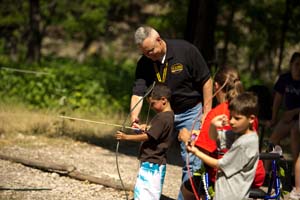 AW2 Director COL Jim Rice teaches AW2 kid Drayson Hill the fundamentals of archery at Operation Purple®, a camp for the children of wounded warriors hosted by NMFA.