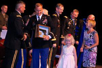 Prudence Siebert Command and General Staff College Commandant Lt. Gen. Robert Caslen Jr. congratulates top U.S. Intermediate Level Education graduate Maj. Richard Martin, accompanied on stage by his wife Julie Martin and daughters 2-year-old Lydia (shaking CGSC Command Sgt. Maj. Philip Johndrow's hand behind her father) and 6-year-old Lillian, during graduation for ILE class 2011-01 June 10 at the Lewis and Clark Center. Martin received the General George C. Marshall Award. Norwegian Capt. Aleksander Jankov received the General Dwight D. Eisenhower Award, presented to the top international graduate.