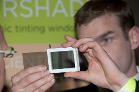 A man demonstrates the technology for a new electrochromic window using a handheld model.