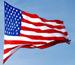 American flag waving in the wind against a blue sky background.