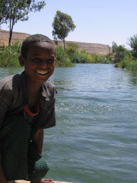 a smiling boy by a river