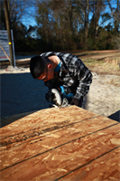 Pfc. David Decasas, a student with the Center for Naval Aviation Tactical Training, cuts a piece of plywood during a Habitat for Humanity volunteer project in New Bern Saturday. Every few weeks Marines head to the build site location and spend several hours hammering away making steady progress.