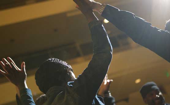 Photo of people with upraised arms touching hands.