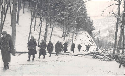 Members of the 104th Infantry marching though the snow soon after their attack of Christmas day. Photo courtesy of the National Archives and Records Administration.