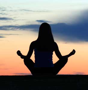 Silhouette of a young woman meditating.