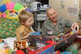 Col. Rick Gibney, 119th Wing commander, helps 3-year-old cancer patient John Freer open his Christmas presents Dec. 23 at Sanford Hospital, Fargo, N.D. 