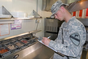 SPC Jeffrey Davis, a preventive medicine specialist for the 15th Brigade Support Battalion, examines a food-preparation table at a food vendor on Forward Operating Base Warrior in Kirkuk, Iraq. (Photo by PFC Justin Naylor)