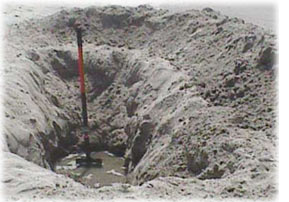 Photo of a large hole dug at the beach showing an example of the water table, below which all the soil is saturated with water.