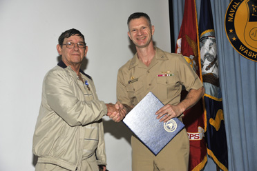 Arthur Merat receives the Navy Meritorious Civilian Service Award from Captain Anthony Ferrari.