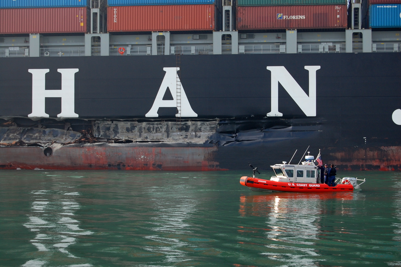 US Coast Guard skiff examines damaged side of M/V Cosco Busan.