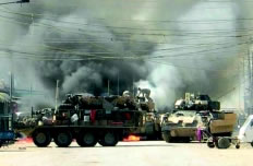 SSG Christopher Waiters climbs onto a burning Bradley Fighting Vehicle (center) to rescue injured crewmen during a firefight in Old Baqubah, Iraq. (Photo provided by Fort Lewis, Wash.)