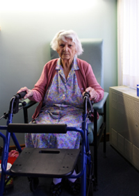 elderly woman with a walker in front of her sitting in a chair