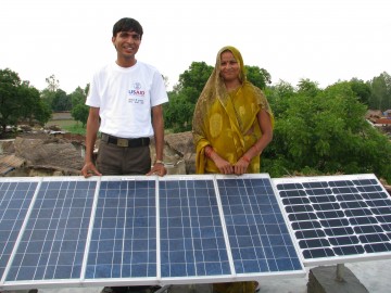 Couple standing behind some solar panels in a field