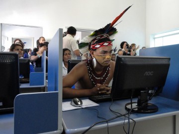 Man dressed in tribal garb using a computer in a classroom