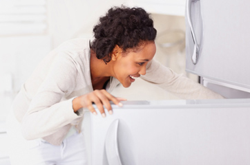 Photo of a woman looking into a refrigerator.