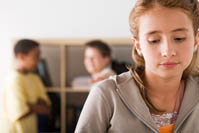 Two boys laughing at a girl looking hurt.