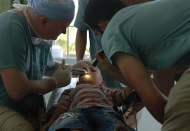 Photo: CAPT John Smith, a dentist, performs a dental procedure on a Vietnamese child at a Pacific Partnership dental civic action program.