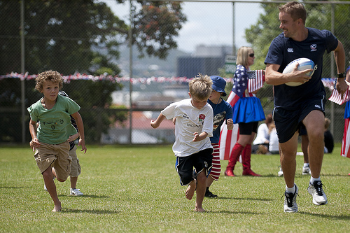 A member of the coaching staff playing touch rugby with the children.