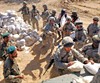 PASHMUL, Afghanistan (October 5, 2006) - Afghan soldiers and U.S. Soldiers from Logistical Task Force 297 unload humanitarian supplies for needy villagers in Pashmul. Photo courtesy of the Department of the Army.
