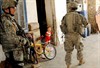 ADHAMIYAH, Iraq (October 5, 2006) - U.S. Army Capt. Mike Baka, left, and Spc. Marvin Ayala, right, both assigned to the 1st Battalion, 26th Infantry Regiment, 2nd Brigade Combat Team, 1st Infantry Division, enter a housing area in Adhamiyah, Iraq, Sept. 24, 2006, where several displaced families are staying to avoid the violence in their own neighborhoods. Photo by Petty Officer 1st Class Keith W. DeVinney, U.S. Navy.