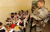 KIRKUK, Iraq (October 5, 2006) - U.S. Army Pfc. Aaron Croussore, Bravo Company, 2nd Battalion, 35th Infantry Regiment, 25th Infantry Division, talks to students as fellow Soldiers and Iraqi Police officers hand out school supplies during a visit to an elementary school in Kirkuk. Photo by Master Sgt. Steve Cline, U.S. Air Force.