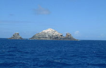 Sea approach to Gardner Pinnacles. Bird guano covers the steep cliffs 