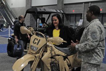The Army is partnering with the automotive industry and others in an effort to jump-start the development of more energy-saving and high-performance vehicles, said Katherine Hammack, assistant secretary of the Army for Installations, Energy and Environment, during a visit to the 2013 Washington Auto Show in the Walter E. Washington Convention Center, Feb. 5, 2013. Hammack also visited industry innovators and exhibits at the auto show, which featured "green car" technology from a number of U.S. and foreign auto makers. Here, Lt. Col. Shannon Jackson, from Rapid Equipping Force, discusses the features of an Army tactical motorcycle and the lightweight tactical all-terrain vehicle behind it.