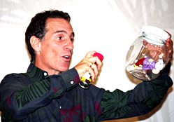 Trevor Romain, a noted children's author and advocate, demonstrates the power of using storytelling and visual aids to reach military children during the Defense Department's Joint Family Readiness Conference in Chicago, Sept. 2, 2009. As an example, he held up a toy mouse inside a glass bowl. Just as nothing he sprays on the bowl reaches the mouse, he said, children can “shield” themselves from mean remarks. DoD photo by Elaine Wilson