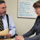 Woman and man talking over desk.