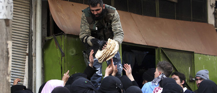 A member of the Free Syrian Army gives bread to people in Aleppo