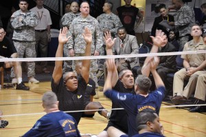 Soldiers playing sitting volleyball block at the net