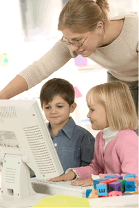 teacher assisting a boy and a girl at a computer