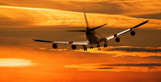 Plane in sky against sunset