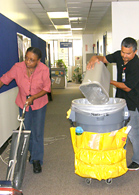 Service persons vacuuming and emptying garbage can