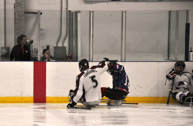 San Antonio Rampage sled hockey player Sgt. Dorian Leon, No. 18, gets checked by a Colorado Avalanche player during the opening game of the San Antonio Rampage Sled Hockey Tournament at the Ice and Golf Center at Northwoods in San Antonio, Feb. 8, 2013.