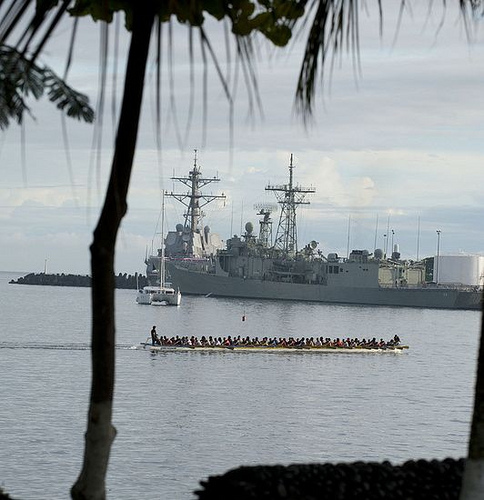 A traditional Samoan fautasi races past the USS Chafee berthed in Apia Harbor.